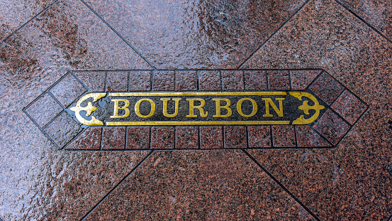 Bourbon Street sign at sidewalk of downtown district, New Orleans.