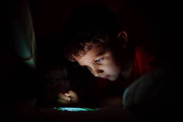 istock Addicted little boy playing games on phone in bed at night. 1406780700