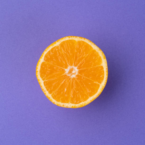 istock Orange half isolated over purple textured background 1406781531
