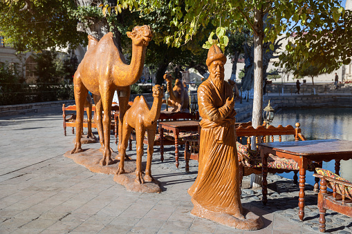 Bukhara, Uzbekistan - October 19, 2016: Sculpture of cameleer and caravan of camels near Lyabi Hauz pond in Bukhara