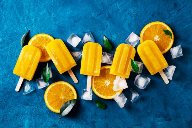 istock Ice cream popsicle orange with ice cube and green leaf on blue background 1406782005