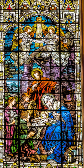 An antique stained glass window depicting the Nativity of Jesus Christ with Mary and Joseph