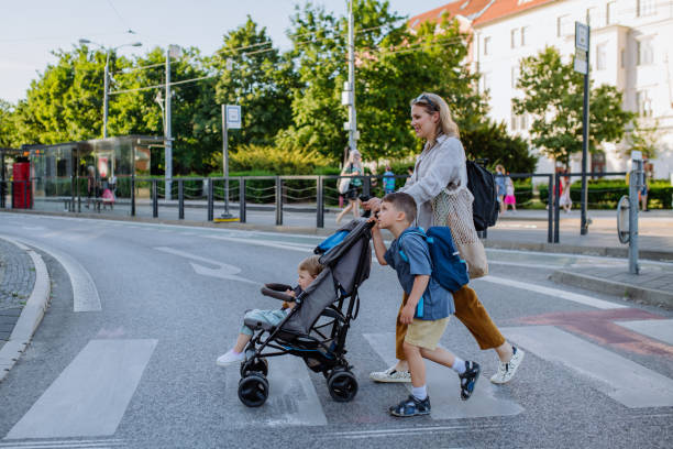 istock Young mother with zero waste shopping bag holding hands with her child and pushingstroller when walking in city street 1406783000