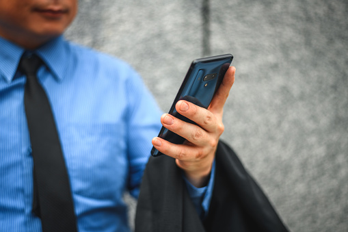 Close-up shot of a professional businessman holding a smart phone. He is using a phone to work and communicate with his team.