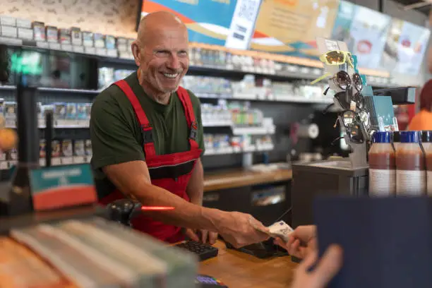 An employee taking cash payment from costumer in gas station, close-up