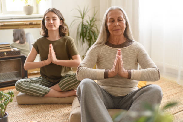 babcia z wnuczką siedząca na podłodze i medytująca w domu - yoga flexibility two people women zdjęcia i obrazy z banku zdjęć