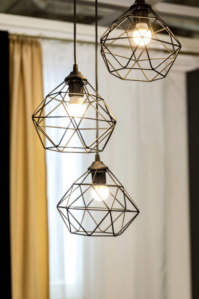 istock Modern wire ceiling lights. Three modern wire lampshades with glowing LED lamps in the interior. 1406785998