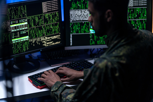 A hacker in military unifrorm on dark web, cyberwar concept.