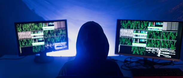 istock Rear view od hooded hacker by computer in the dark room at night, cyberwar concept. 1406786978