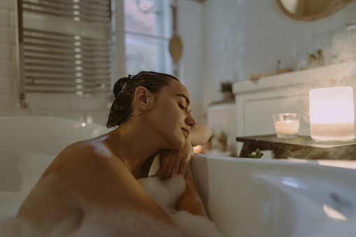 Photo of a young woman enjoying aromatherapy while taking a bath.