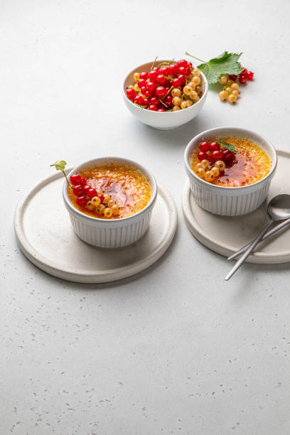 creme brulee, cream brulee, burnt cream with currant in ramekins. traditional french vanilla cream dessert with caramelised sugar on top. homemade dessert with berries. copy space. selective focus. - custard creme brulee french cuisine crema catalana imagens e fotografias de stock