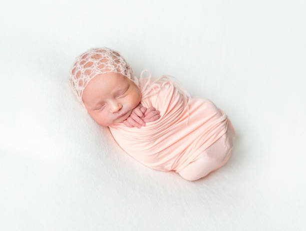 istock Sleeping newboen baby in a pink wrap 1406793963