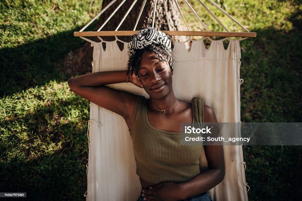 Woman relaxing in a hammock Black woman relaxing in a hammock outdoors in back yard Relaxation Stock Photo