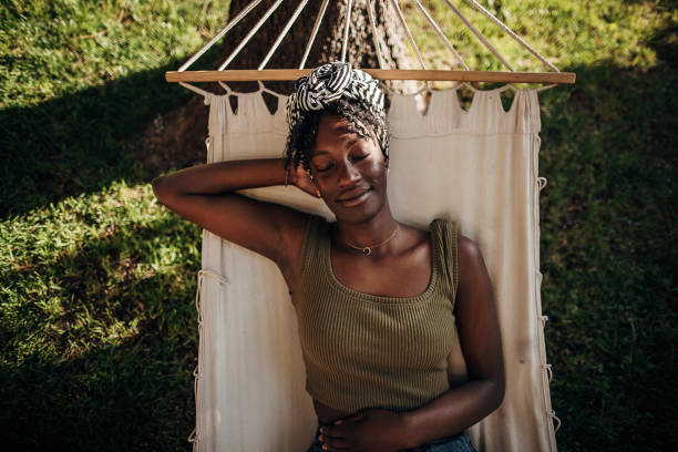 Woman relaxing in a hammock Black woman relaxing in a hammock outdoors in back yard serene people stock pictures, royalty-free photos & images