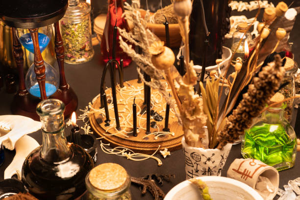 istock Witchcraft still life with black burning candles selective focus. Esoteric gothic and occult witch table for Halloween. Various magic objects and ritual arrangement. Gothic Halloween. 1406812374