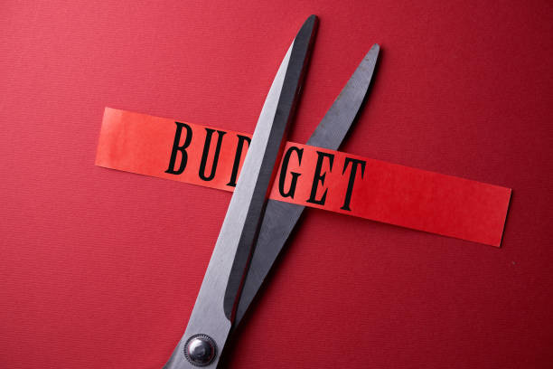 istock scissor cutting paper with western script budget on red background 1406824239