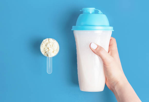 Female hands hold bottle of protein shake and a measuring spoon with protein powder, top view Female hands hold bottle of protein shake and a measuring spoon with protein powder, top view Dosing of gym stock pictures, royalty-free photos & images