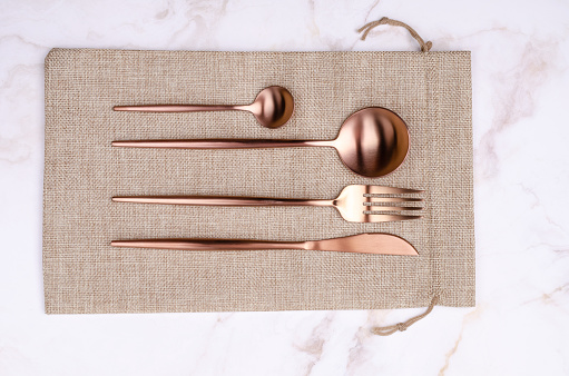 Shiny textured spoon and fork, made of copper. The brown metal cutlery has an used touch and is isolated on white. High resolution close-up image.