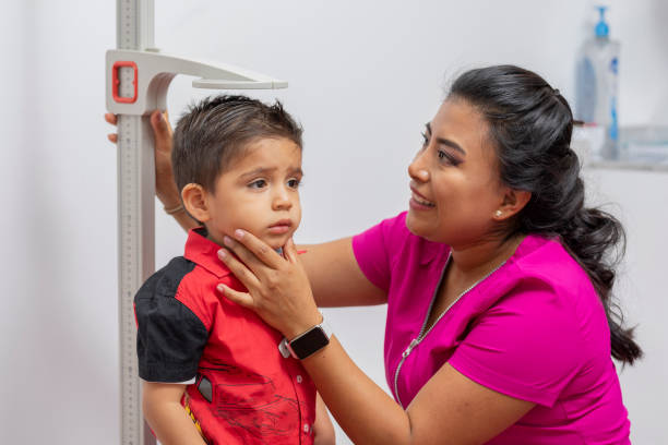 close up of a female pediatrician doctor measuring a child's height with a pedestal ruler close up of a female pediatrician doctor measuring a child's height with a pedestal ruler. boy height measure stock pictures, royalty-free photos & images