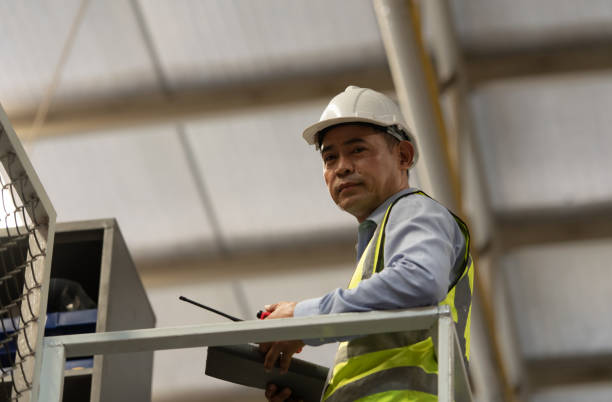 gerente de almacén con el papel de administrar y controlar los productos que deben venderse a los minoristas en tiempos de precios de mercado más altos - manual worker portrait helmet technology fotografías e imágenes de stock