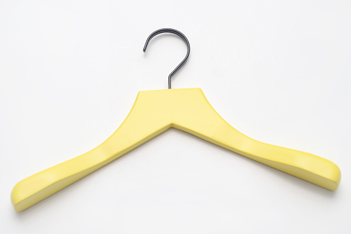 Closeup of a yellow wood hanger on a white background.