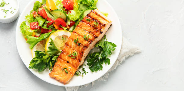 istock Salmon steak with vegetables and fries on light background. 1406837034