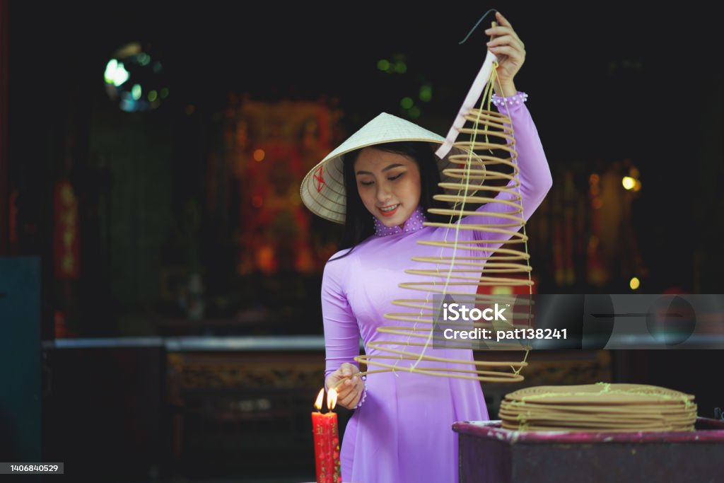 Vietnamese woman in traditional dress praying Vietnamese woman in traditional dress praying with incense stick in the burning pot of the Chinese temple, Ho Chi Minh Vietnam Vietnam Stock Photo