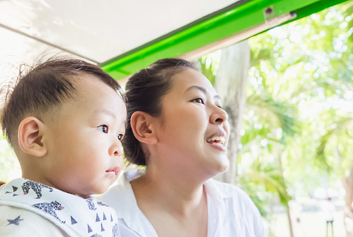 Shot of mother and her little son sit on tram in summer day at the zoo. Concept of friendly family and vacation