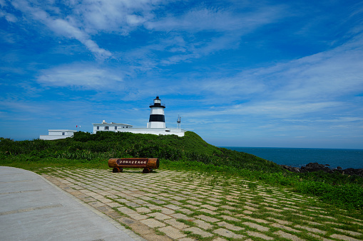 Fugui Cape Lighthouse under the blue sky and white clouds. Black and white wall. The northernmost lighthouse in Taiwan is located in Fugui Cape, Shimen District, New Taipei City.