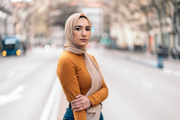 Beautiful young muslim woman standing in the street wearing hijab and looking at camera.