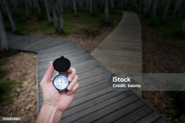 Human Hand Holding A Compass On The Forked Road Stock Photo - Download Image Now - Guidance, Hiking, Navigational Compass