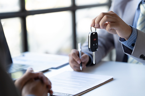 El vendedor de automóviles entregó las llaves a los clientes que firmaron el contrato de compra legalmente, finalización exitosa de las ventas de automóviles, Contrato de compra y entrega de llaves. photo