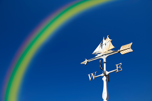 Rainbow over the sailboat weather vane against clear sky.