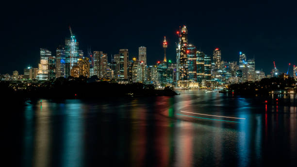 istock Ferry light trails and a colorful cityscape at night. 1406850518