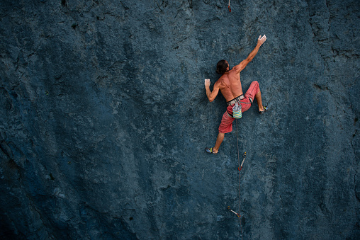 Athletic climber reaching a hold on a steep rock face