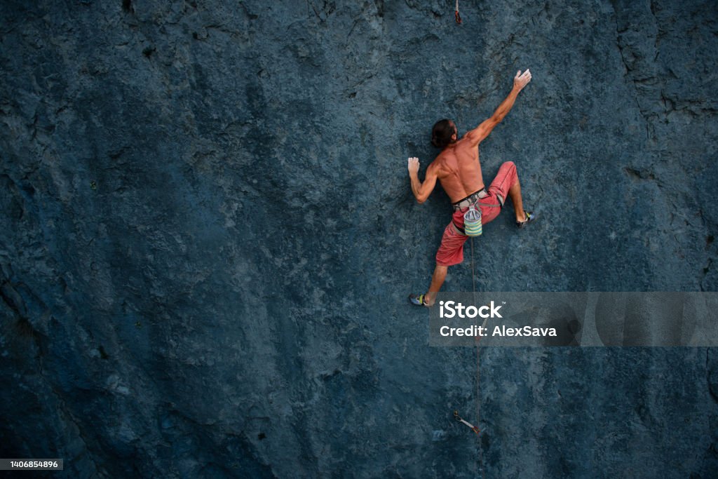 climbing technique Athletic climber reaching a hold on a steep rock face Rock Climbing Stock Photo