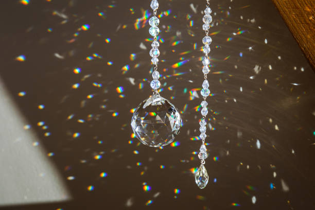 Selective focus on ball and teardrop shape crystal rainbow maker suncatcher hanging in home. Good Feng Shui, Sha Chi energy flow concept. Beautiful spring light in room.