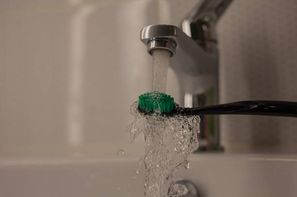 istock Wet toothbrush closeup under running water tap. 1406858018