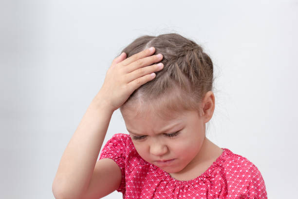 istock Child with headache holding hand on head 1406858790