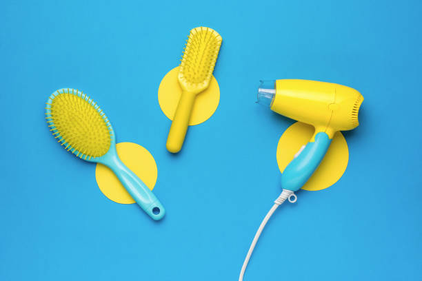 istock Two plastic massage combs and a hair dryer on an abstract blue yellow background. 1406859078