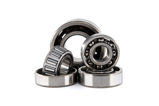 Group of various ball and roller bearings on white background. Spare parts for roller machine in heavy machinery and automotive industry