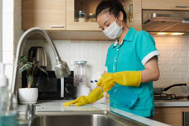 Cleaner disinfecting sink in kitchen Young cleaner in protective gloves and mask disinfecting surface of kitchen table with spray and rag asian maid stock pictures, royalty-free photos & images