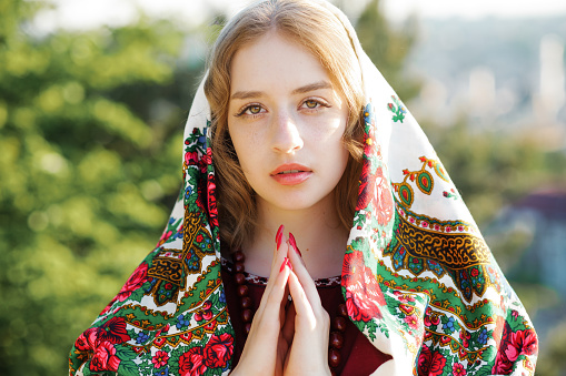 A young Ukrainian girl prays with folded hands to the sky.