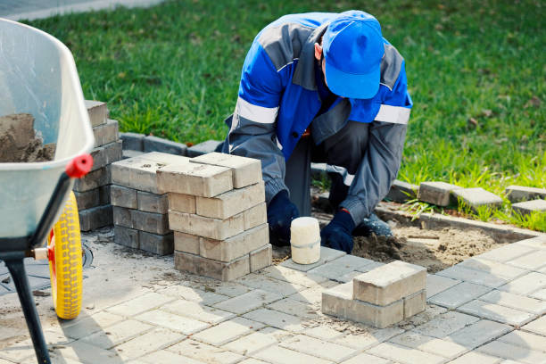 istock Bricklayer lays paving slabs outside. Working man performs landscaping. Builder lays out sidewalk with stone blocks. 1406860896