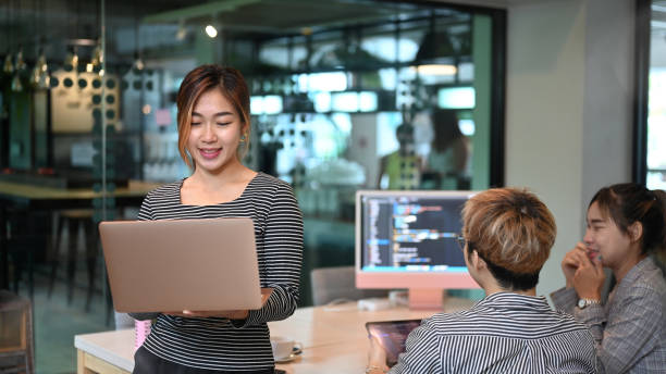 istock Asian female team leader standing in office and software developers team working in background. 1406860975