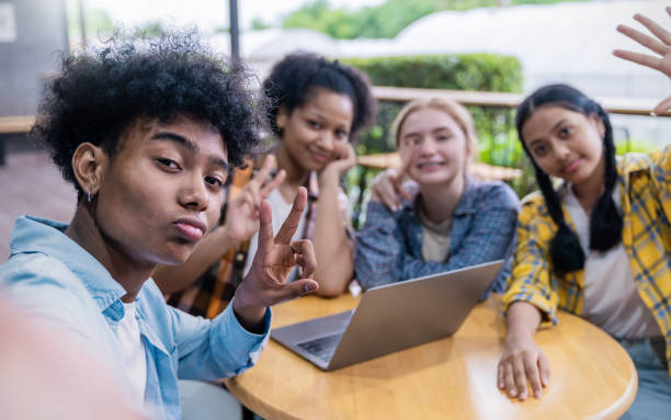 porträt von teenagern mit smartphone selfie sagen hallo an der high school oder universität. die gruppe von glücklichen lustigen teenagern, die selfies im klassenzimmer machen. teamarbeit eines coolen kindes, das computer benutzt, um das projekt zu erle - pazifikinseln stock-fotos und bilder