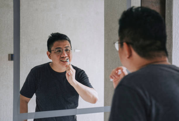 istock Asian chinese mid adult man brushing teeth in bathroom on routine morning 1406863071