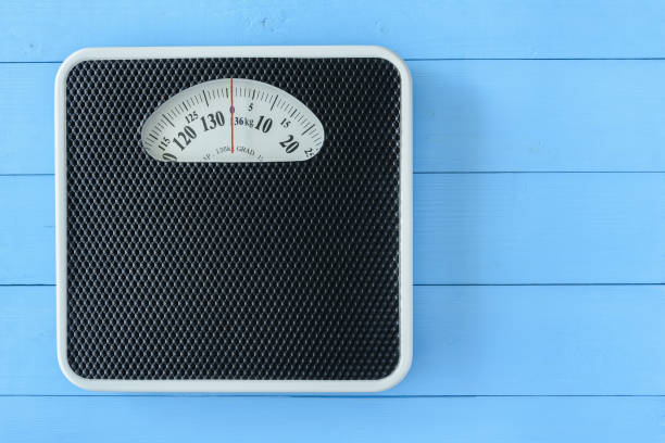 istock Mechanical weight scale, body mass control concept : Bathroom scale on pale blue wood background. Analog scale operated with spring that pressure is calibrated to translate tension into a mass readout 1406863115