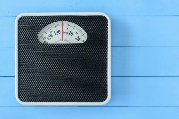 Mechanical weight scale, body mass control concept : Bathroom scale on pale blue wood background. Analog scale operated with spring that pressure is calibrated to translate tension into a mass readout.