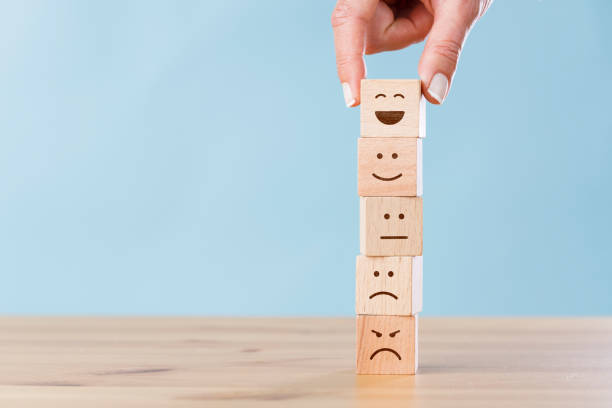 istock Woman hand chooses smiley face on wooden block cube 1406863661